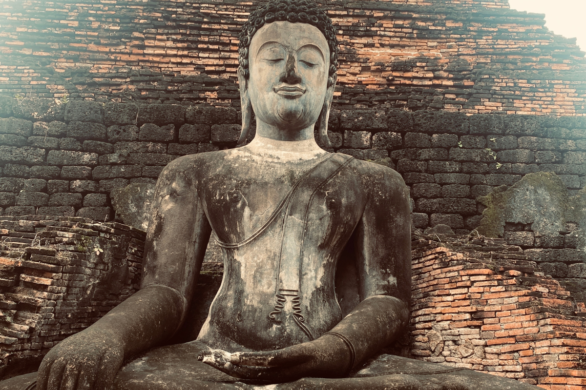 Steinerne Buddha-Statue im historischen Park von Sukhothai, Thailand. Arbeiten als digitaler Nomade