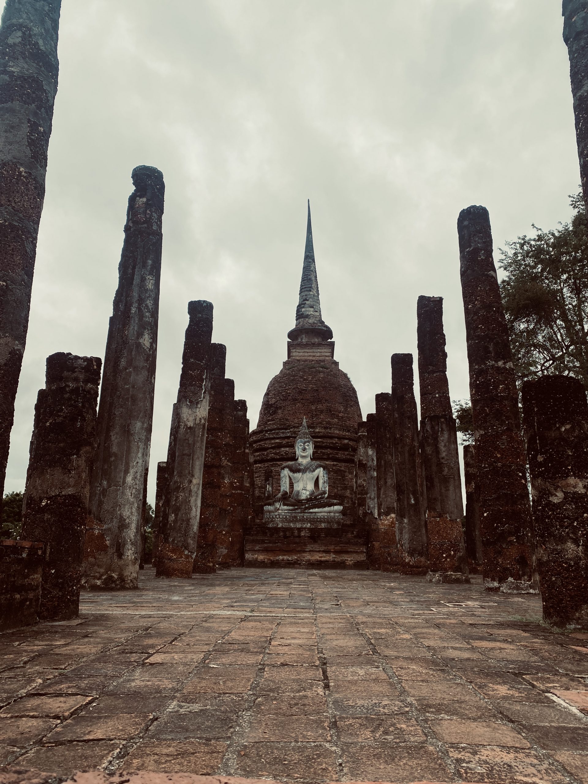 Buddha-Statue inmitten alter Säulen im historischen Park von Sukhothai, Thailand
