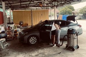 Zwei Personen reinigen ein Auto in einer offenen Werkstatt in Tak, Thailand – eine Szene, die zeigt, dass Erfolg im Business auch durch Entschleunigung und bewusste Pausen entsteht.