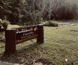 Holzschild mit Aufschrift Welcome to Chae Son Waterfall im Nationalpark Lampang, Thailand